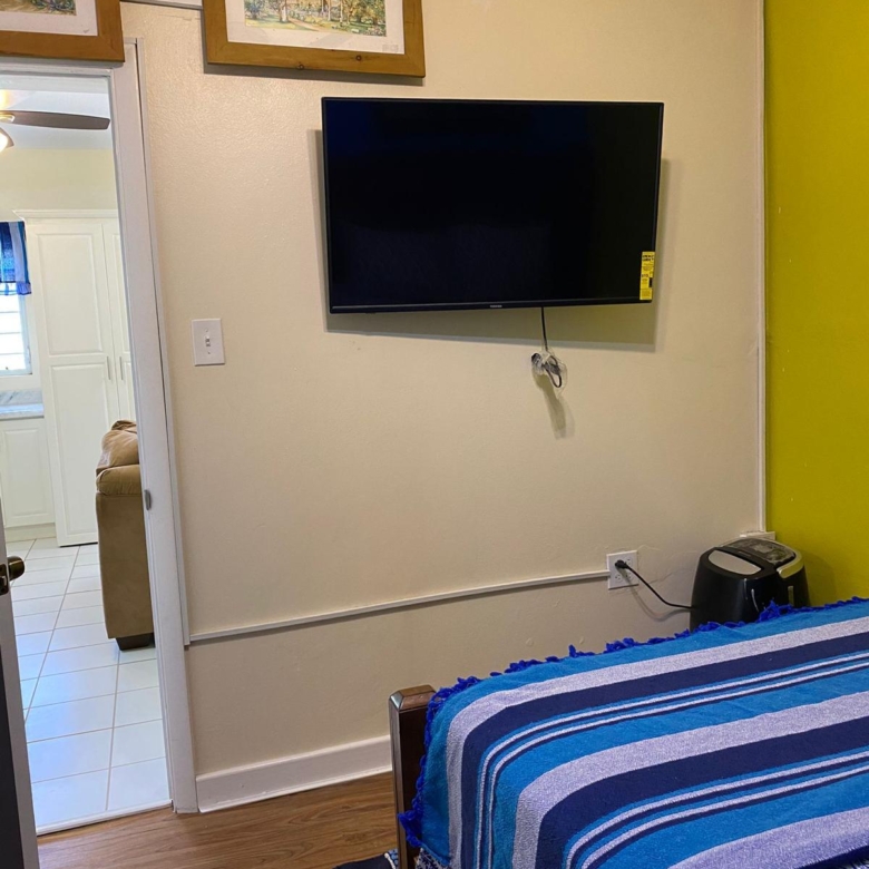 Wall mounted flat screen TV in the bedroom of a furnished 1 bedroom apartment for rent at Crescent Hill, Basseterre