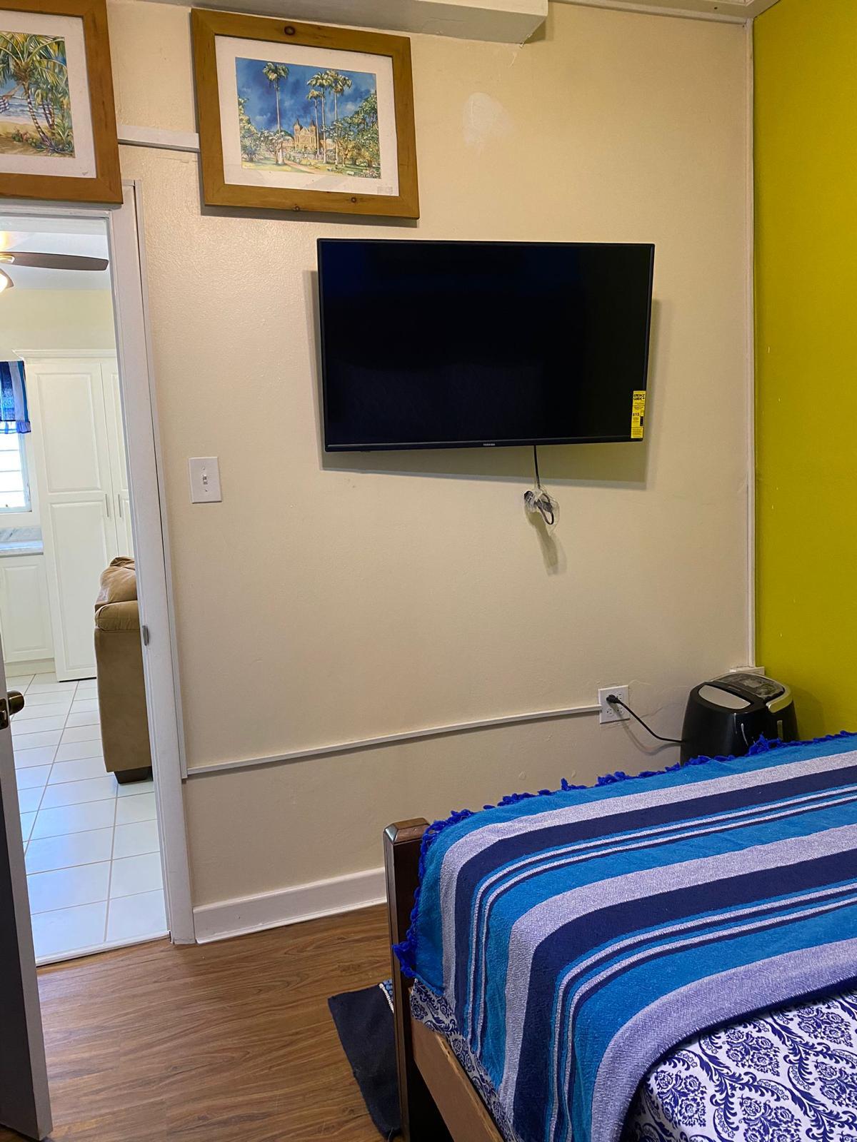 Bedroom TV Wall mounted flat screen TV in the bedroom of a furnished 1 bedroom apartment for rent at Crescent Hill, Basseterre