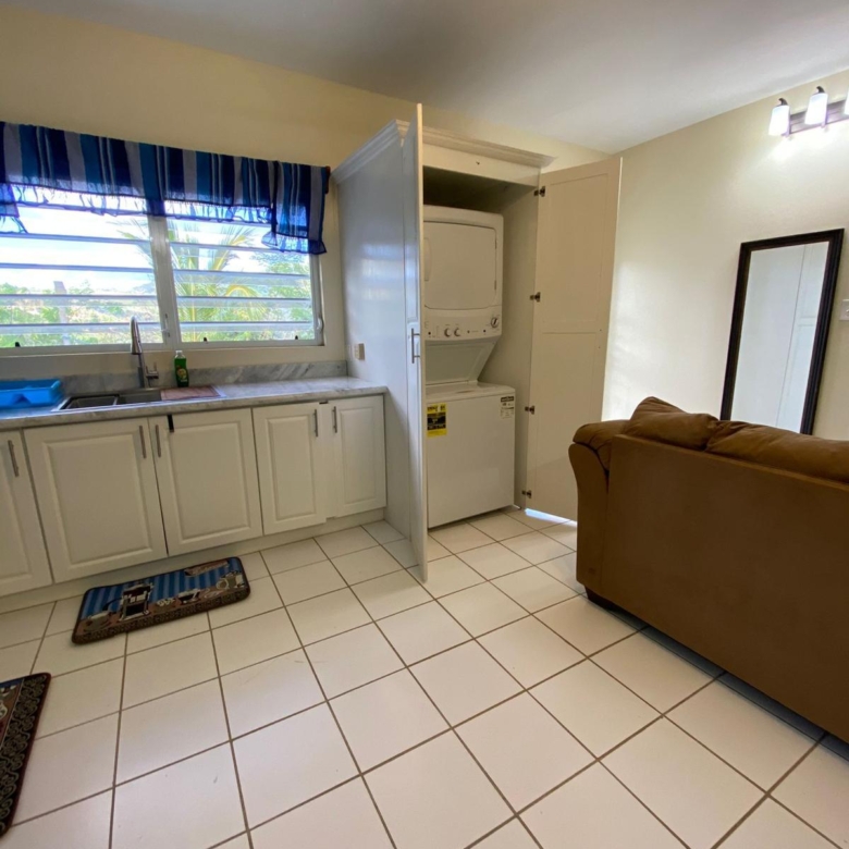 Kitchen sink and in-unit washer and dryer cupboard beside the living area, furnished 1 bedroom apartment at Crescent Hill, Basseterre
