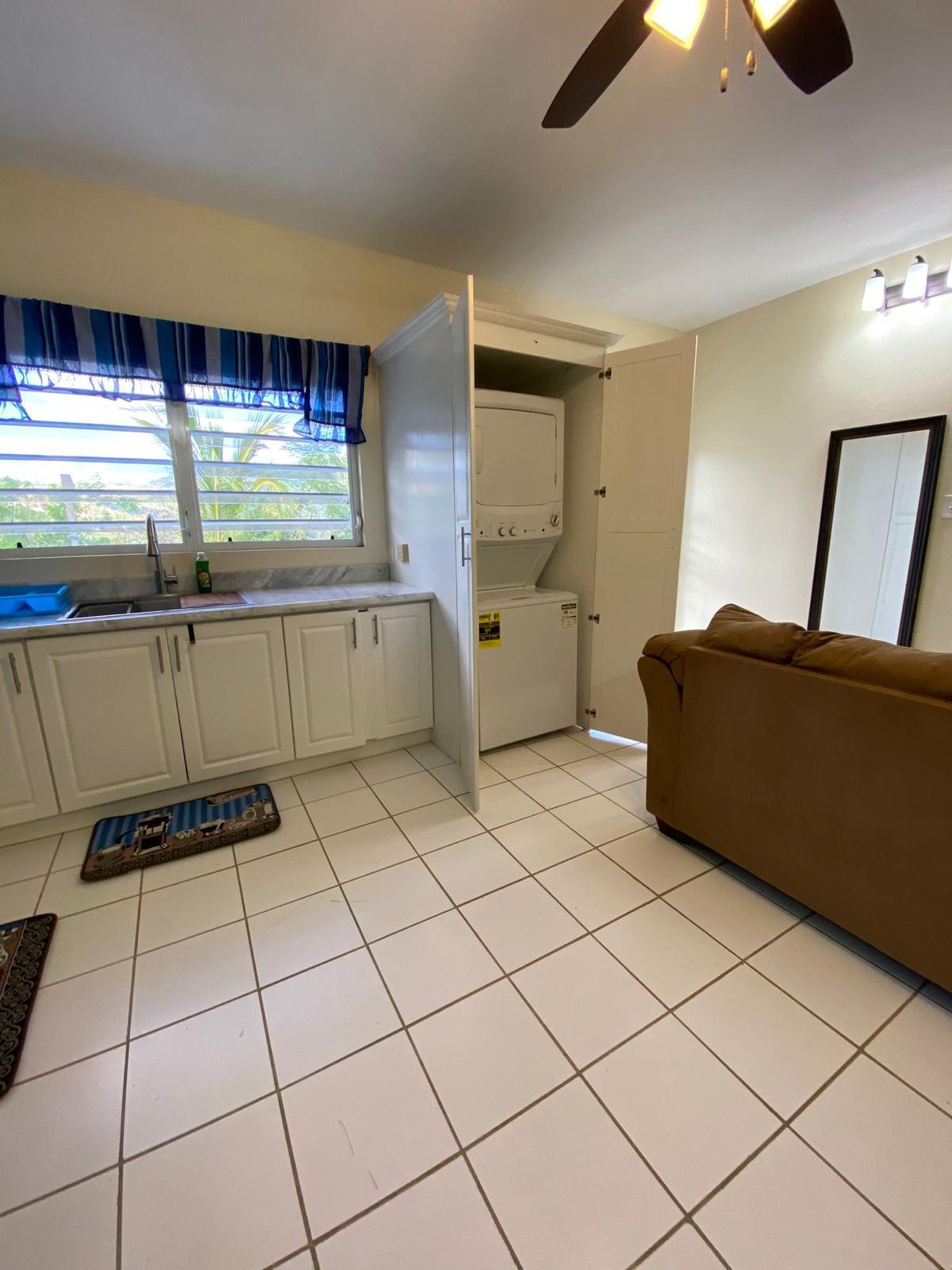 Kitchen and laundry Kitchen sink and in-unit washer and dryer cupboard beside the living area, furnished 1 bedroom apartment at Crescent Hill, Basseterre