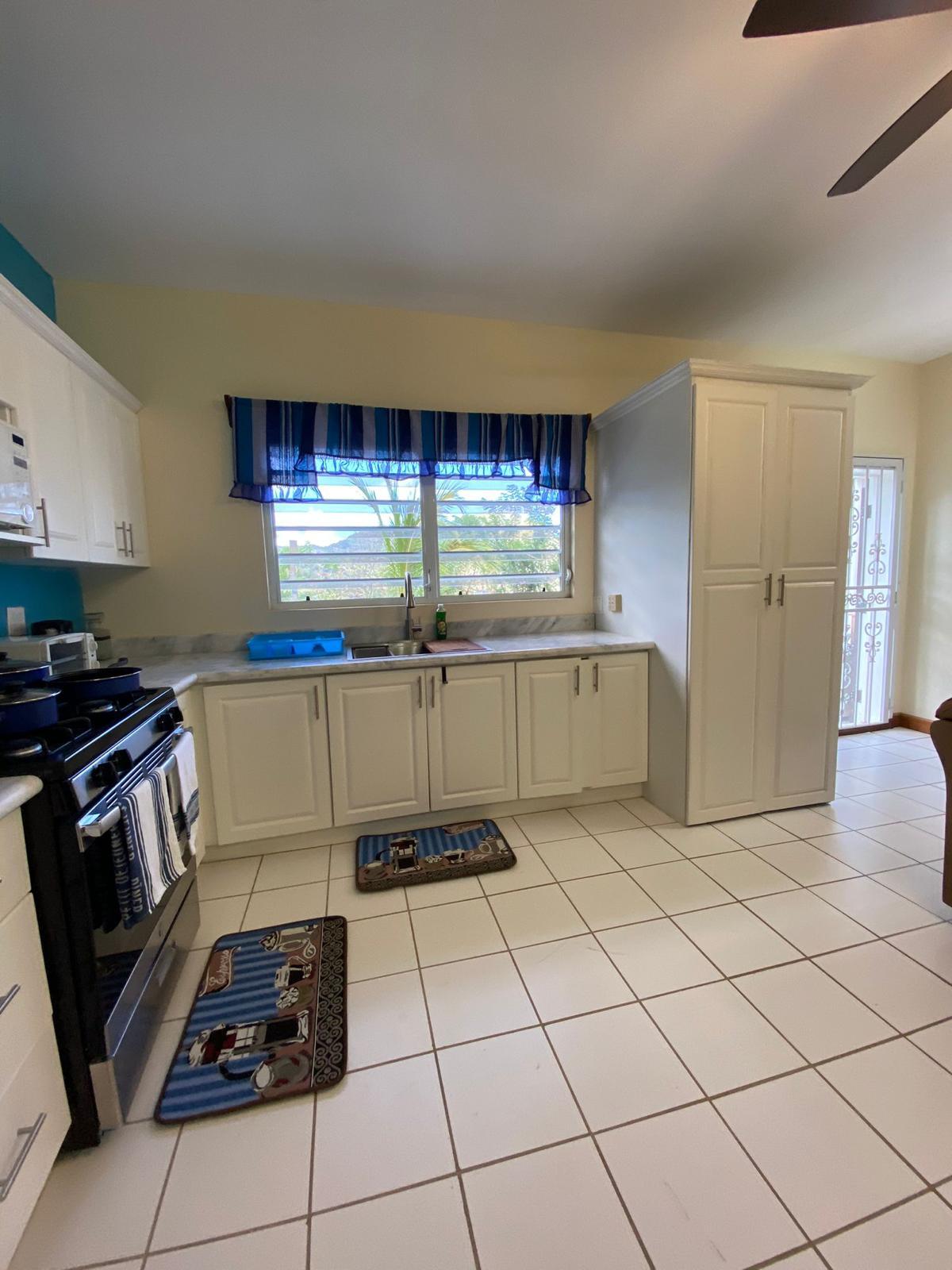 Kitchen Fitted kitchen with gas range, marble worktops and pantry in a furnished 1 bedroom apartment for rent at Crescent Hill, Basseterre