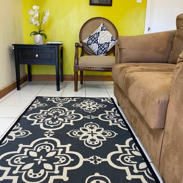 Furnished living room with sofa, armchair and wall mounted TV in a 1 bedroom apartment for rent at Crescent Hill, Basseterre, St. Kitts