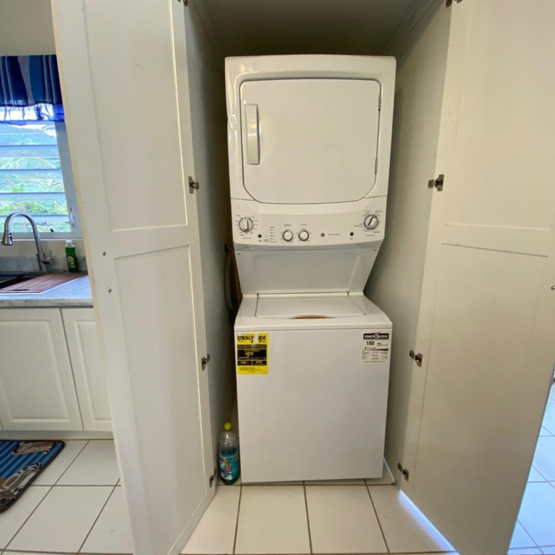 In-unit stacked washer and dryer in a fitted cupboard, furnished 1 bedroom apartment for rent at Crescent Hill, Basseterre