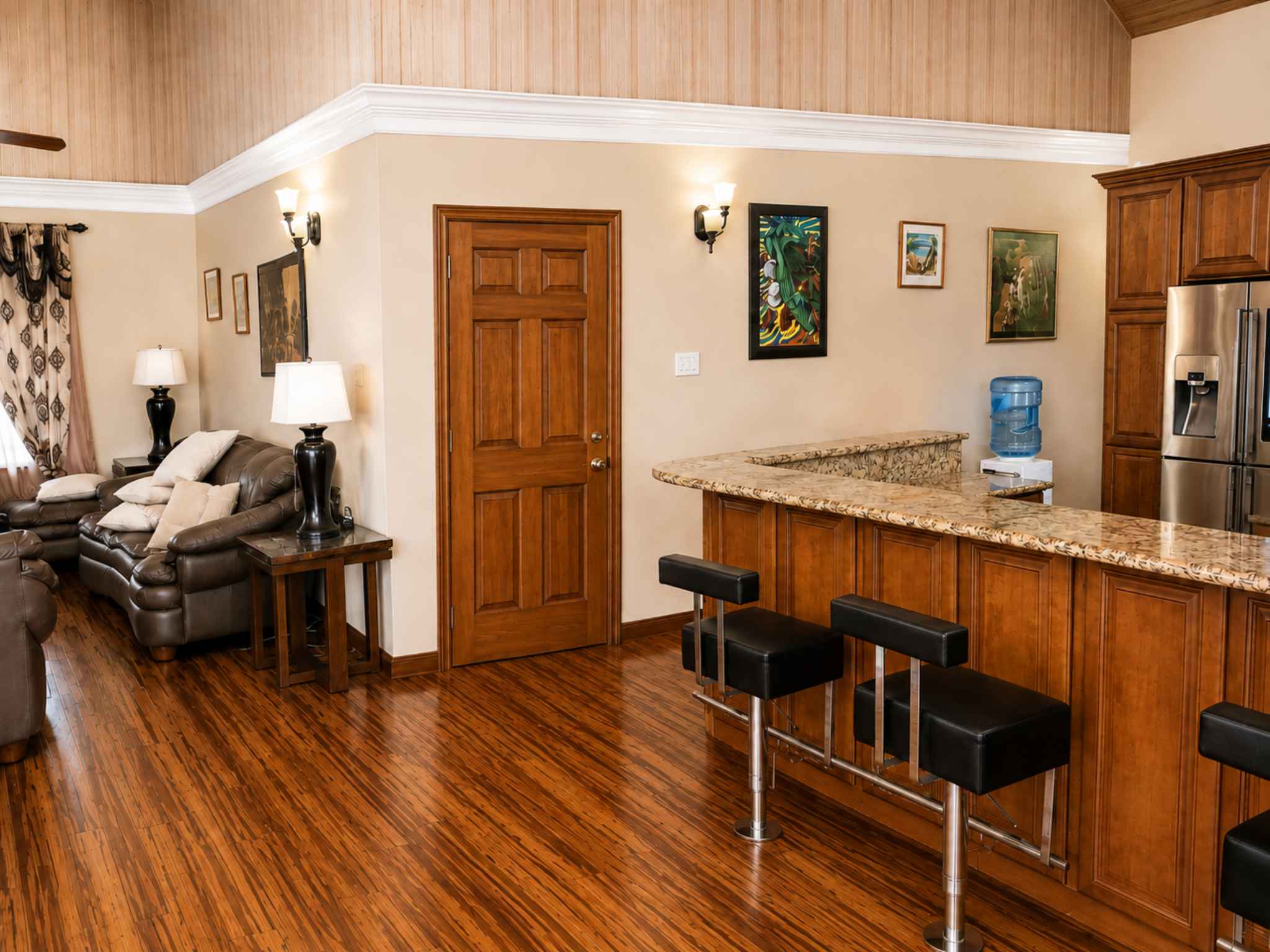 Granite breakfast bar with black stools separating the kitchen from the living area