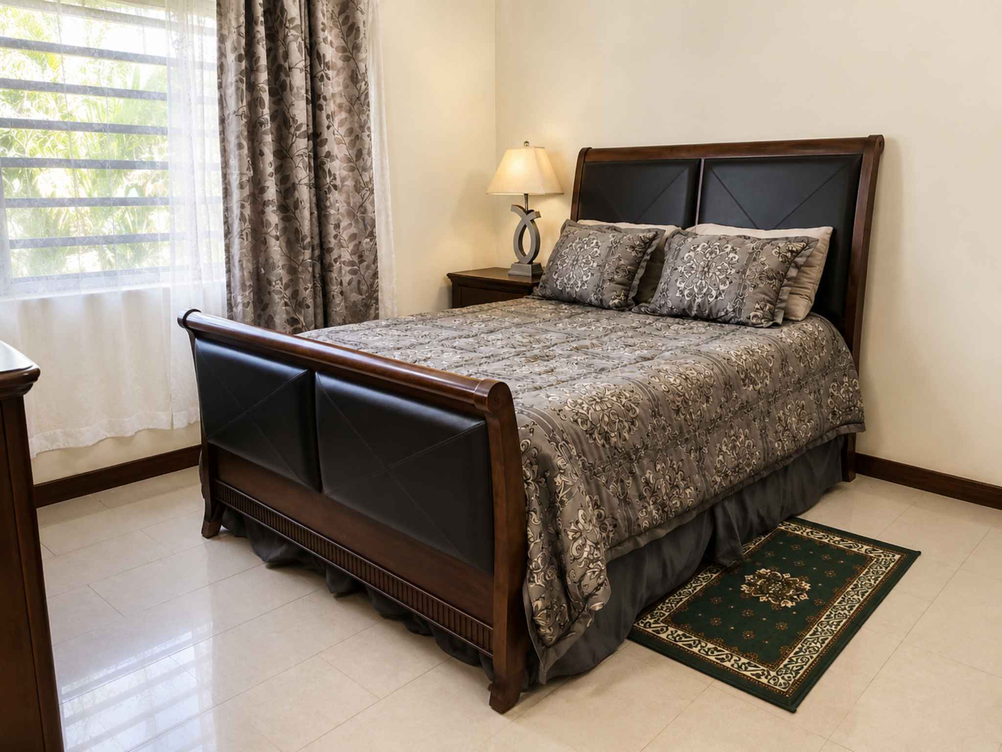 Second bedroom with a dark wood sleigh bed, tiled floor and curtained window
