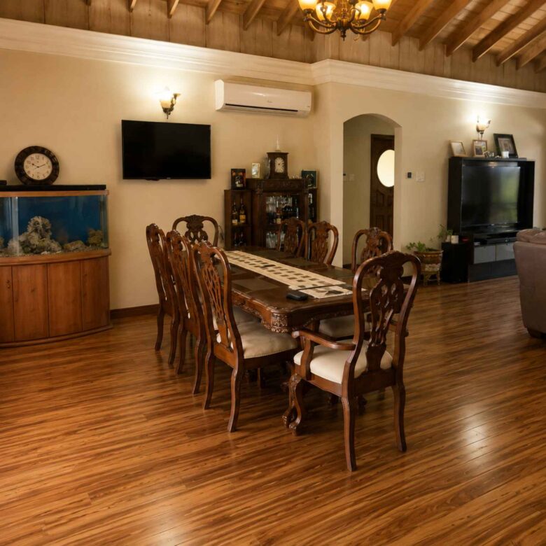 Dining area with a long timber table for eight beneath a chandelier and timber ceiling