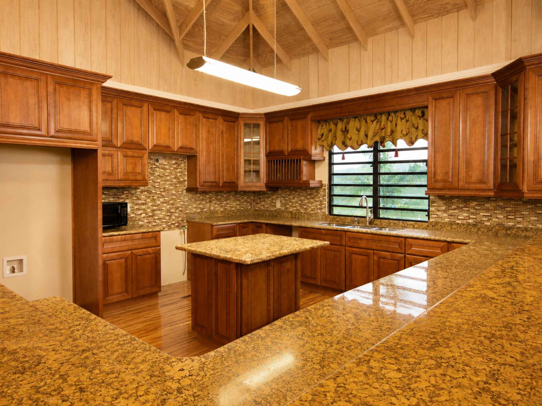 Wraparound timber kitchen with granite counters, central island and vaulted timber ceiling