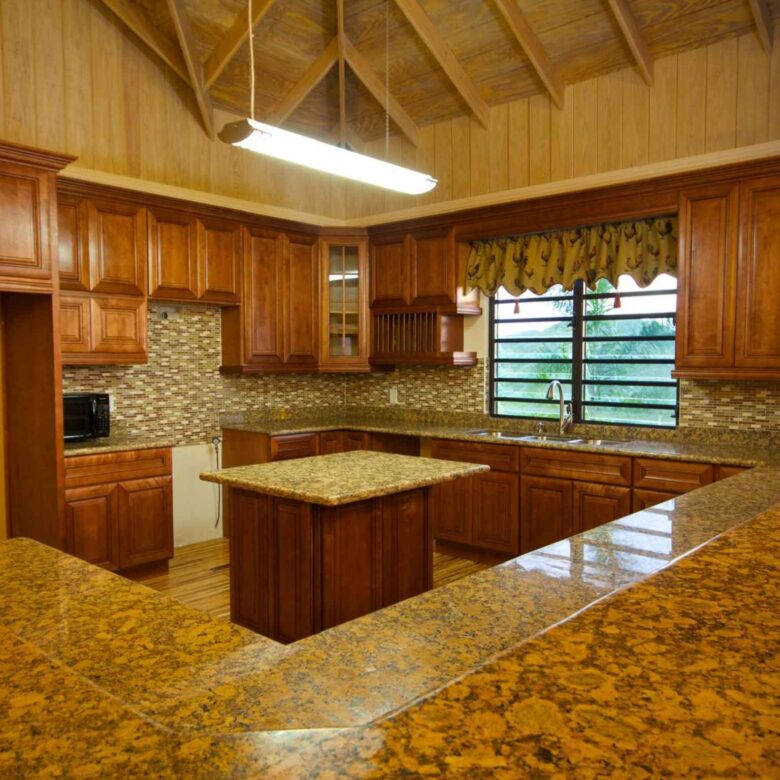 Kitchen granite counters and timber cabinetry beneath the vaulted timber ceiling