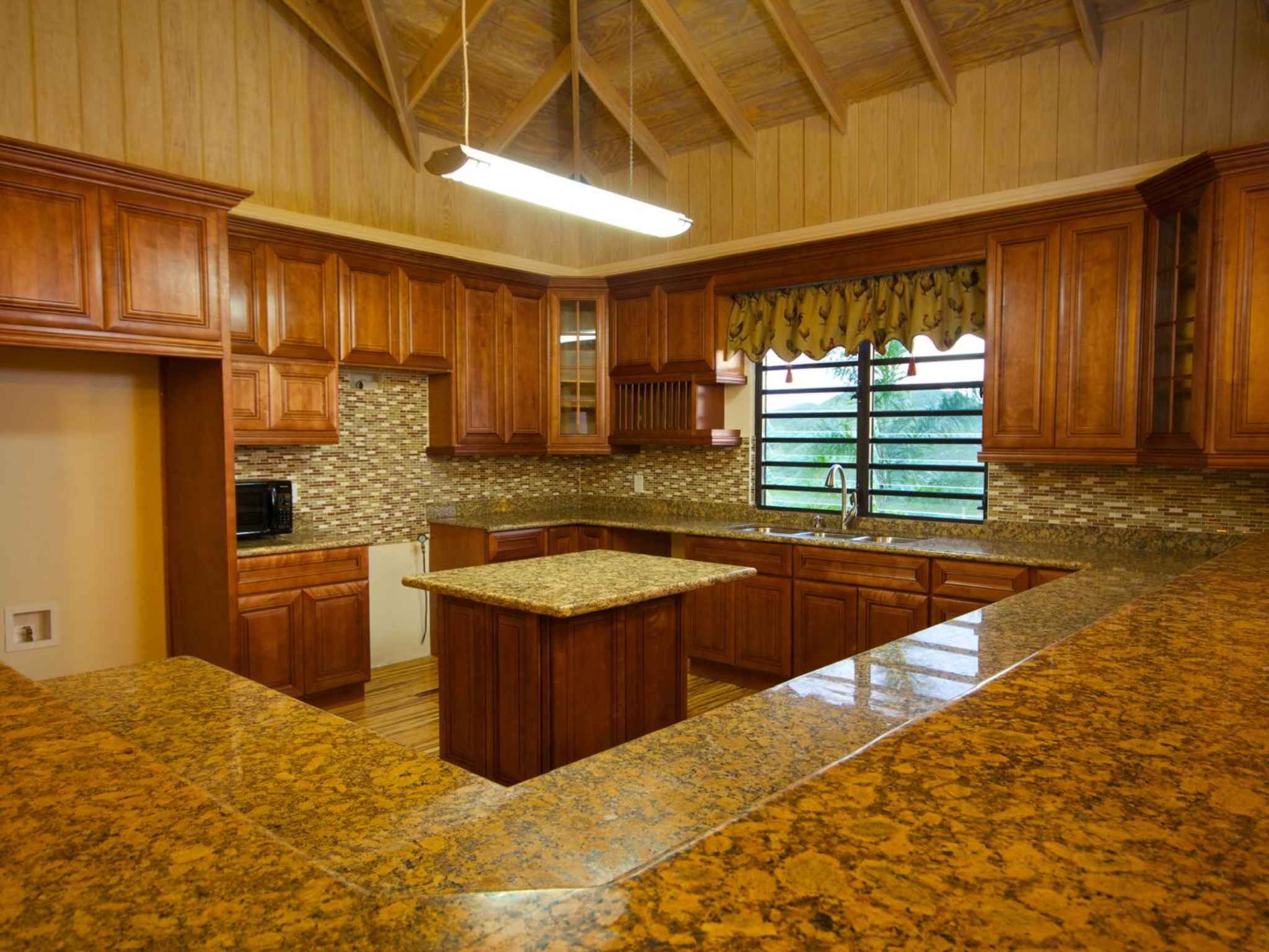 Kitchen granite counters and timber cabinetry beneath the vaulted timber ceiling
