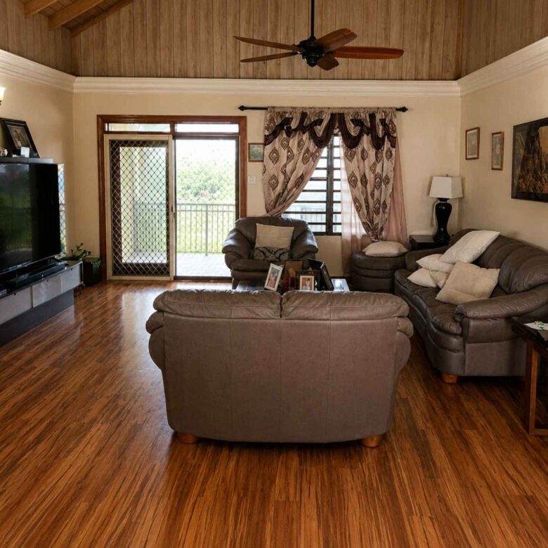 Living area with leather seating, ceiling fan, timber ceiling and doors to the balcony