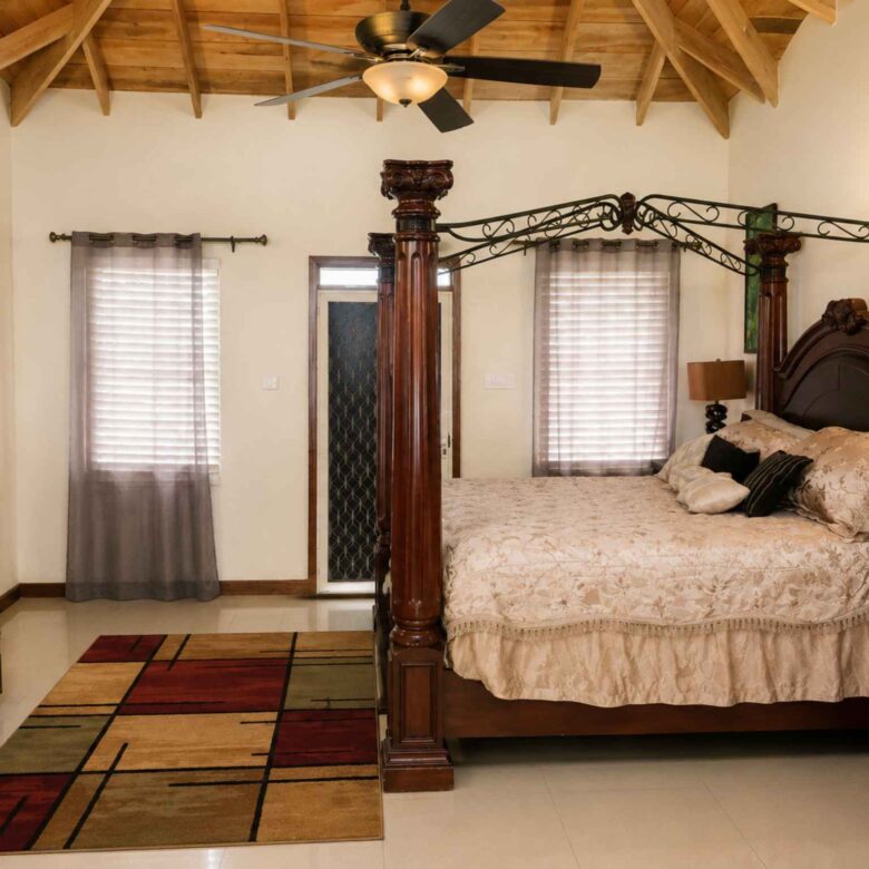 Primary bedroom with a carved four-poster bed, vaulted timber ceiling and tiled floor
