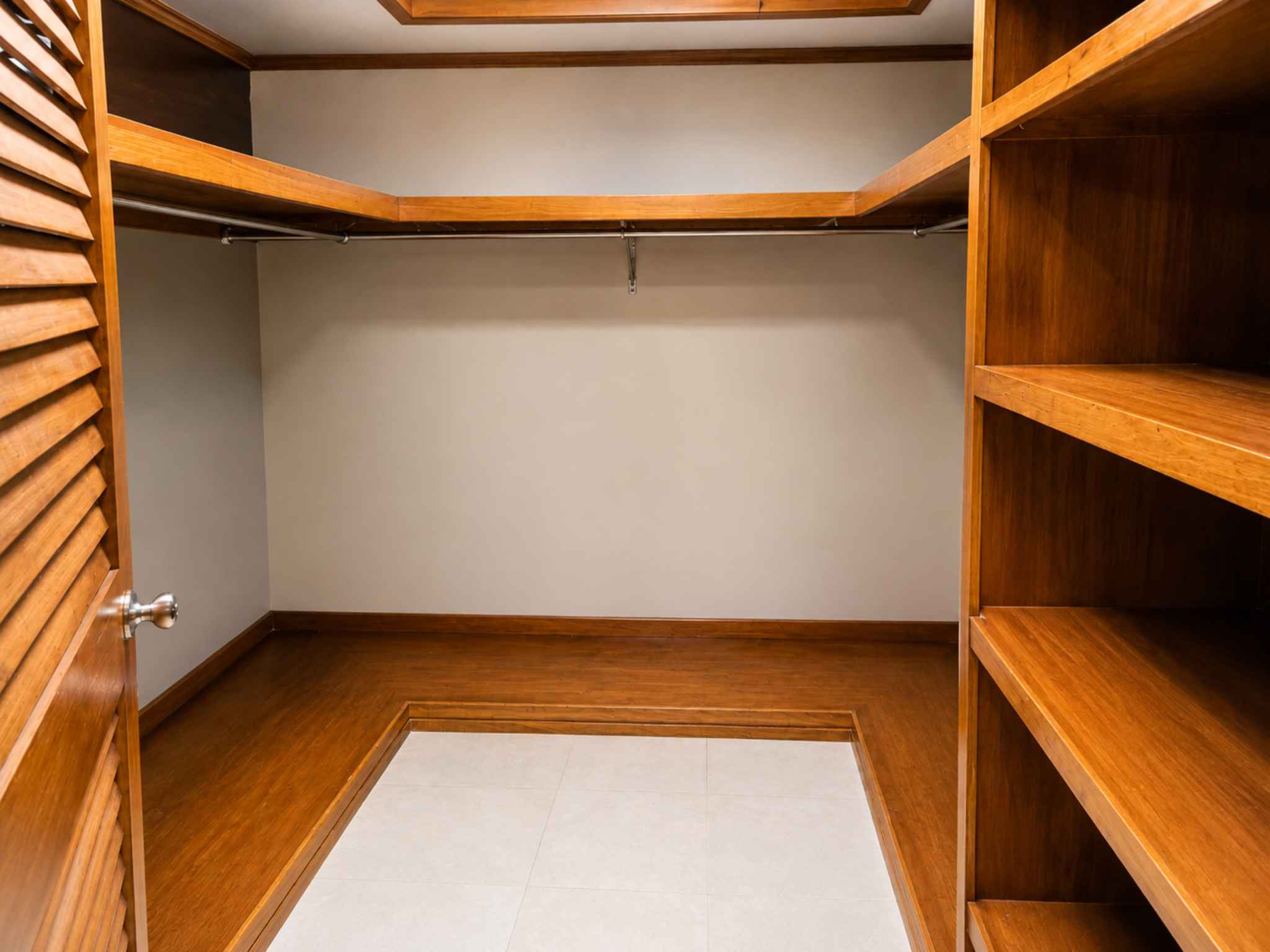 Walk-in closet fitted with timber shelving and hanging rails on multiple sides
