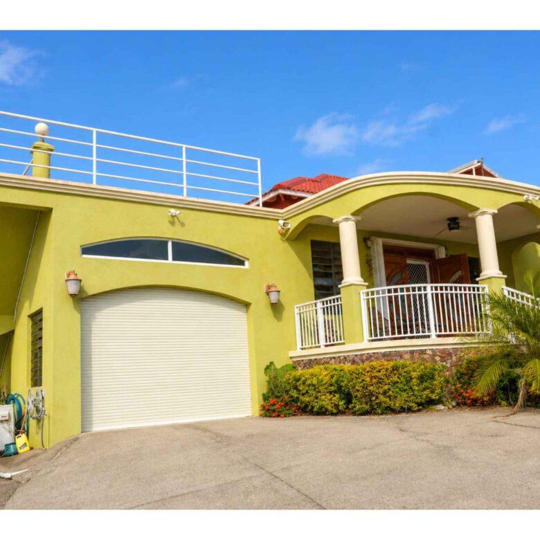 Side of the property showing the garage, covered portico and railed roof deck