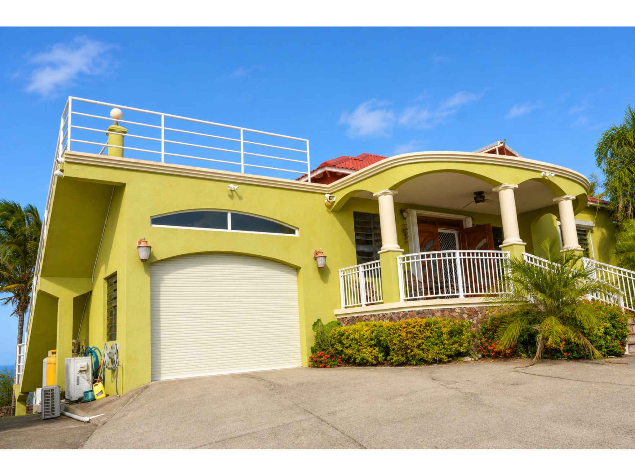 Side of the property showing the garage, covered portico and railed roof deck
