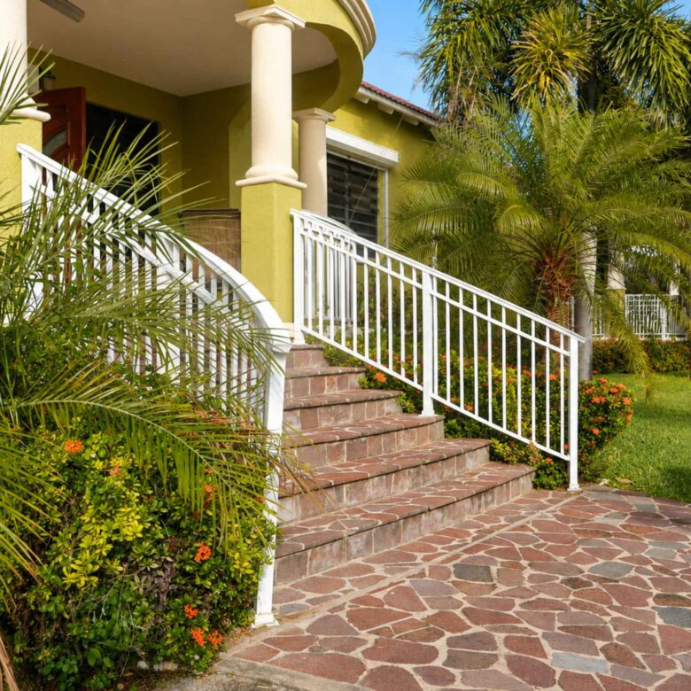 Stone-paved forecourt and tiled steps rising to the covered entrance between palms