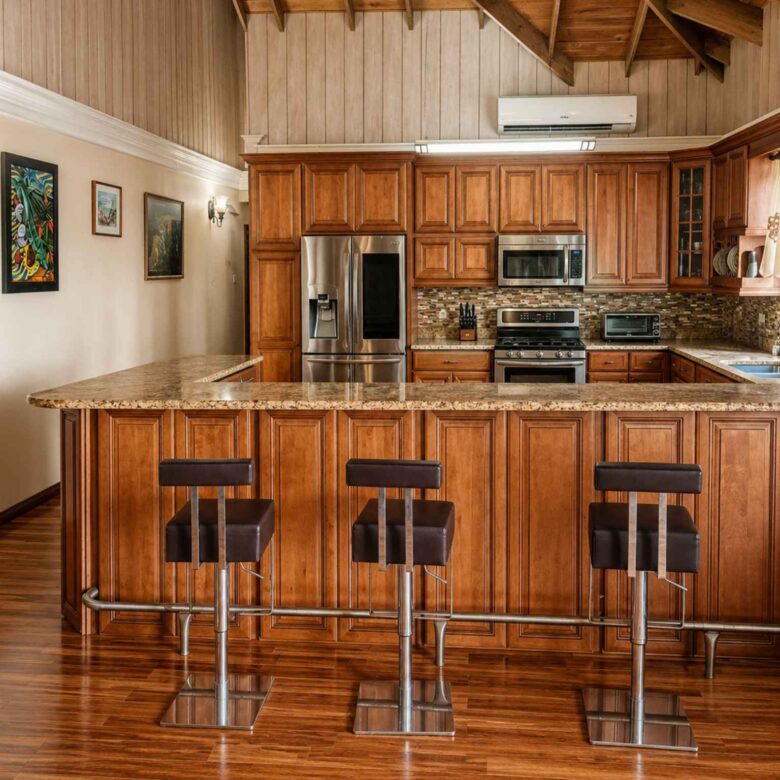 Timber kitchen with granite peninsula, bar stools, stainless steel appliances and vaulted ceiling