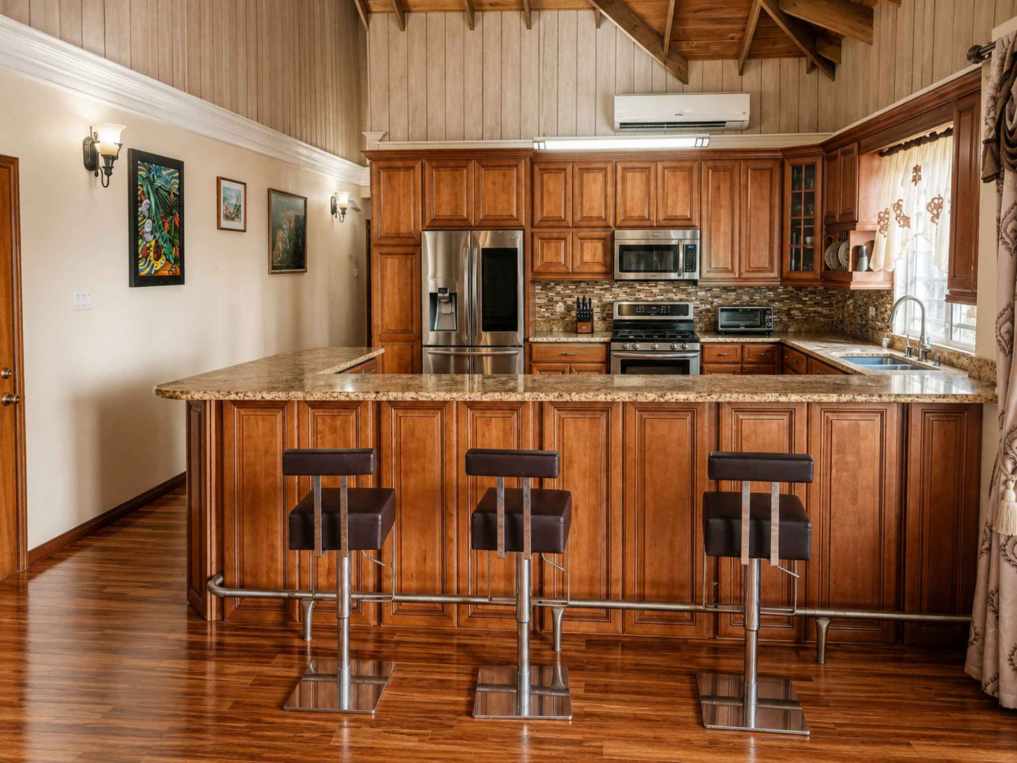 Timber kitchen with granite peninsula, bar stools, stainless steel appliances and vaulted ceiling