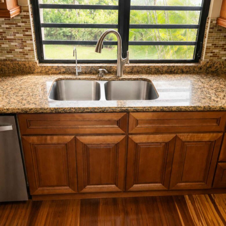 Double-bowl stainless steel kitchen sink set in granite beneath a window