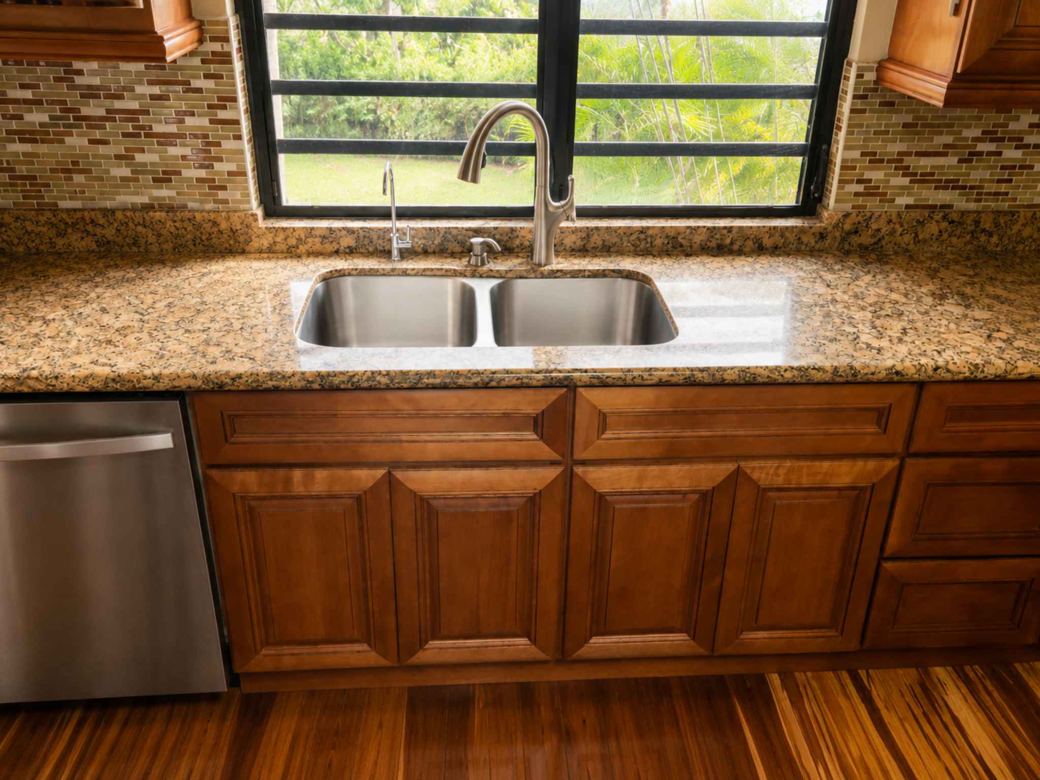 Double-bowl stainless steel kitchen sink set in granite beneath a window