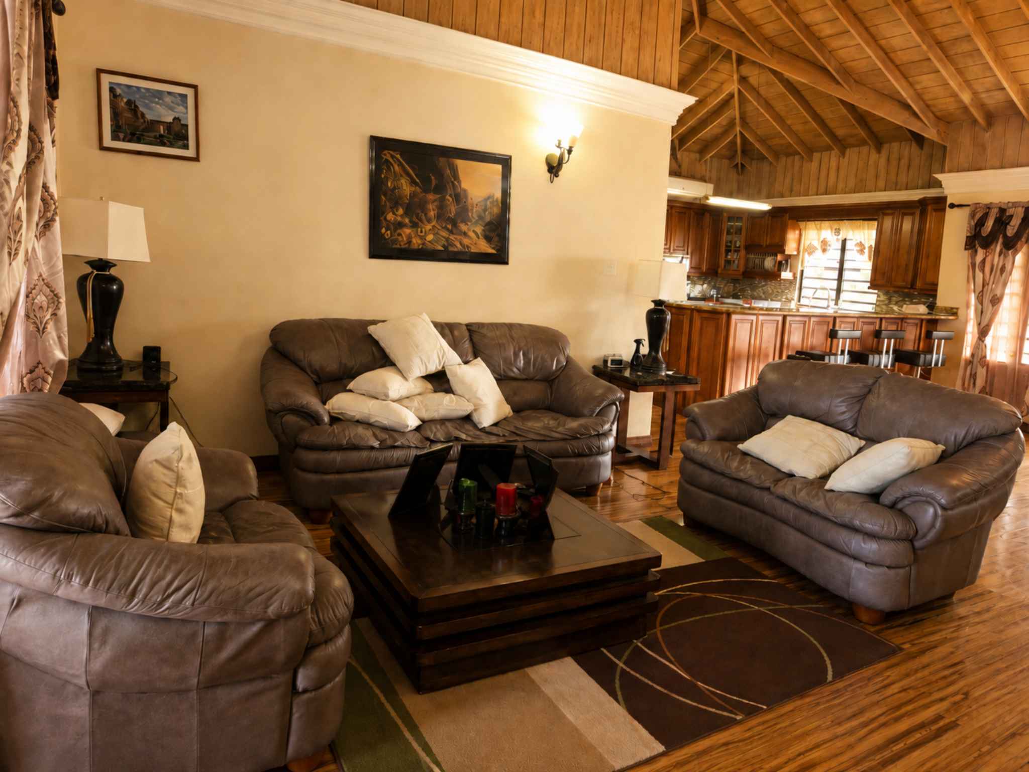 Living area with leather sofas around a low table, kitchen bar visible beyond