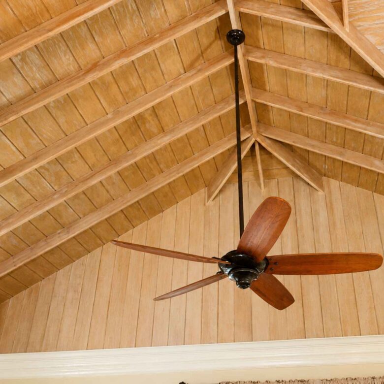Detail of a vaulted timber ceiling with exposed rafters and a wooden ceiling fan